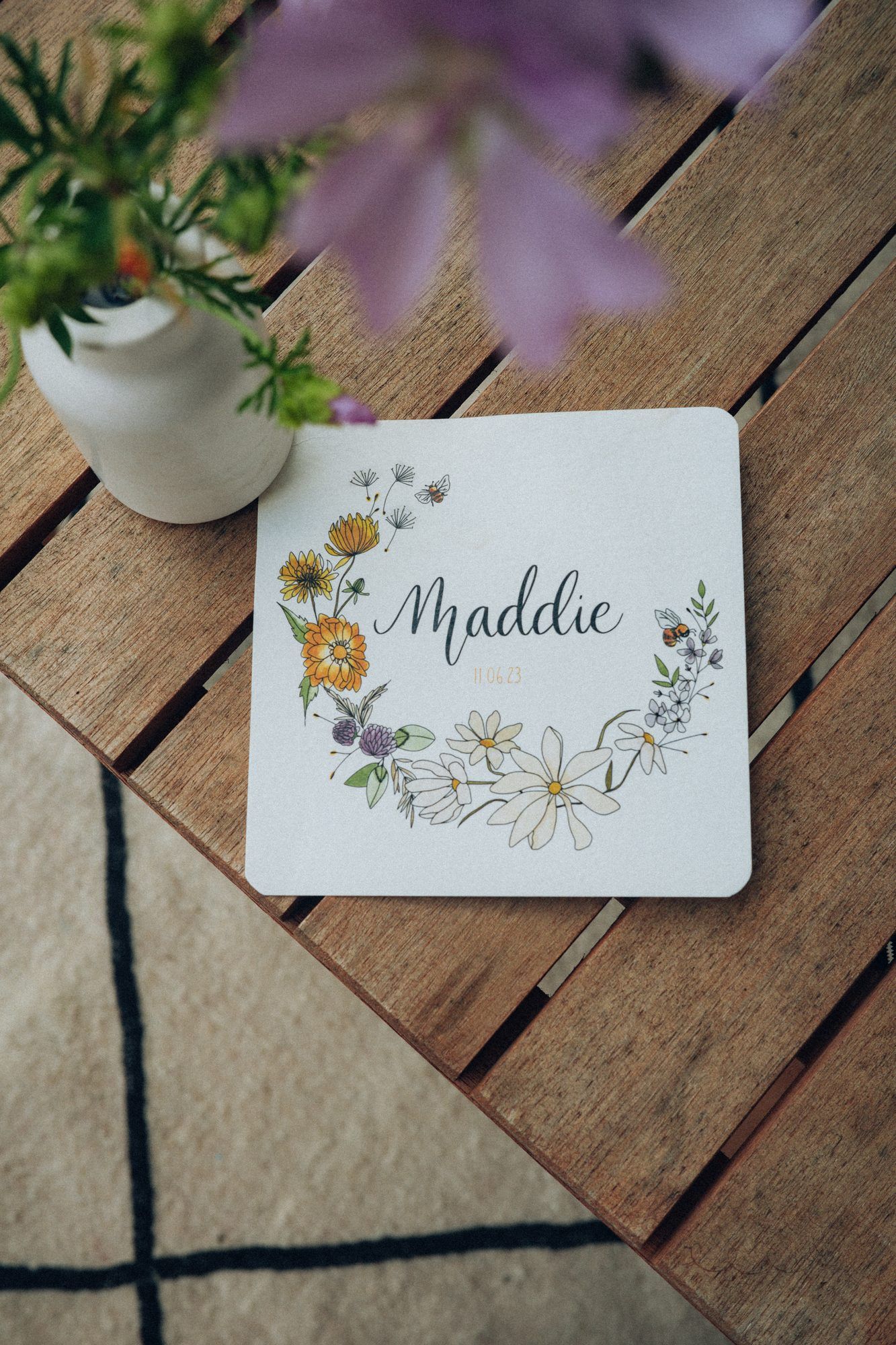 Faire-part de naissance de Maddie, couronne de fleurs des champs, sur une table en bois